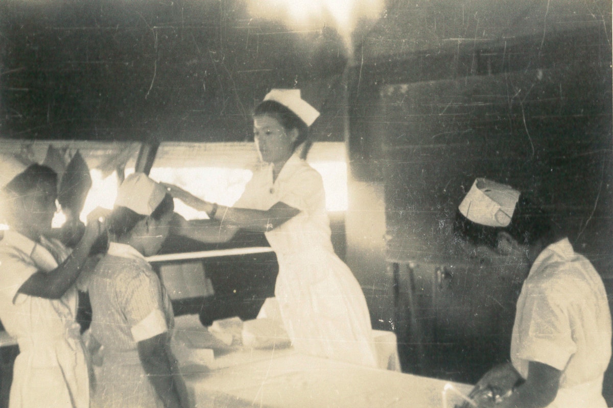 Nurses receiving their nursing caps from Nobu in a Quonset hut-type hospital after the war